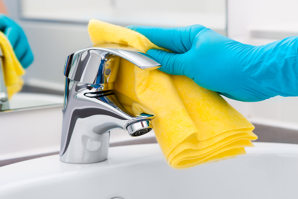 Commercial Cleaning Certifications. Woman doing chores in bathroom, cleaning tap