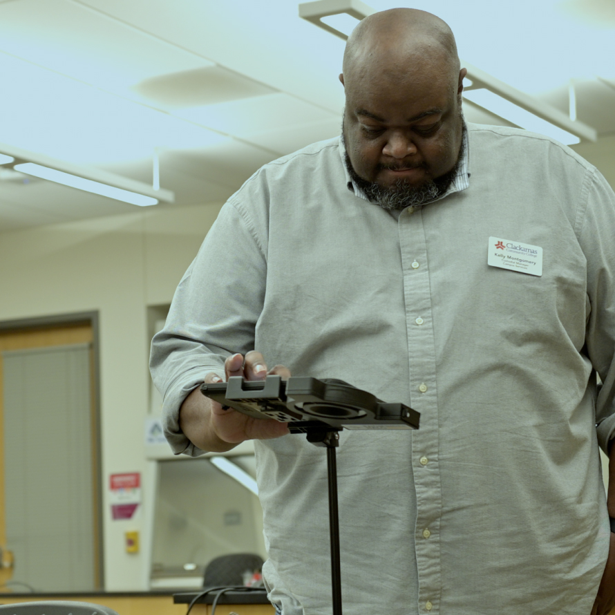 A man wearing a khaki shirt and a name tag bearing the company Clackamas is using Optisolve's Pathfinder to take images of an area of the office.
