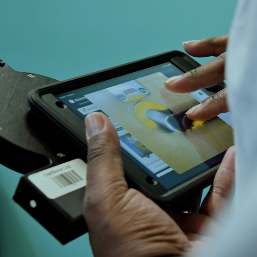 A male is holding the iPad with the optisolve pathfinder attached, while magnifying an image of a door handle that has yellow infrared notes on certain areas of the handle.
